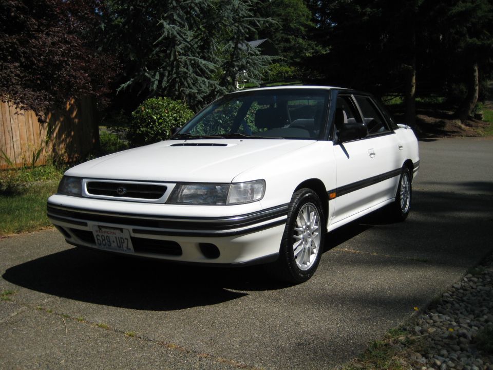 White 1990s Subaru Legacy sedan parked on a driveway.
