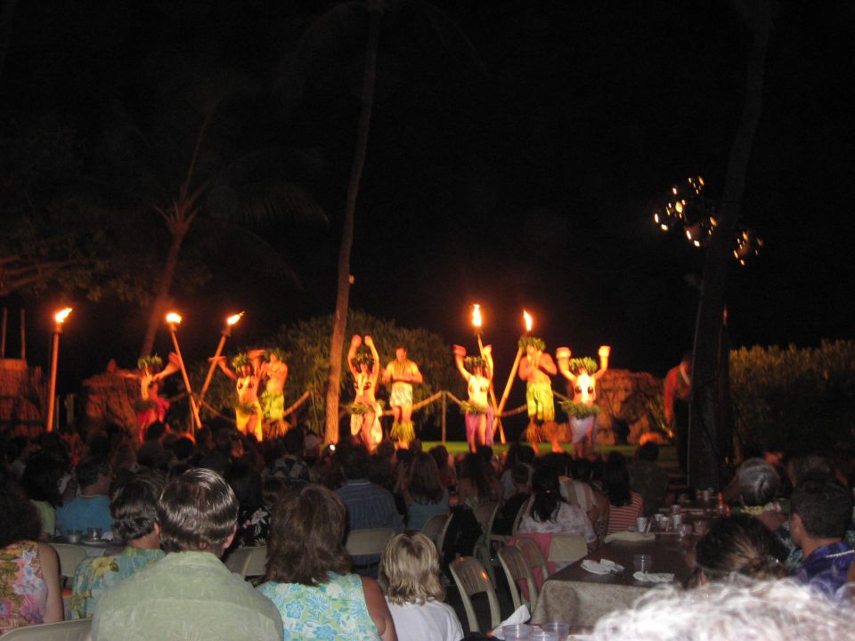 Nighttime luau performance with dancers and torches in front of an audience.