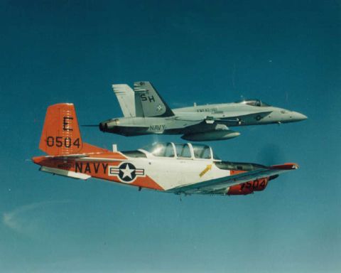 1997 Ford Crown Victoria - Two US Navy trainer aircraft flying in formation against a clear blue sky.