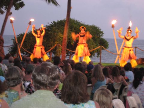 1991 Ford Bronco - A group of hula dancers perform with torches at sunset in front of an audience by the ocean.