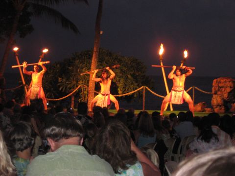 1991 Ford Bronco - A group of performers entertains an audience with a traditional fire dance show on a tropical beach at dusk.