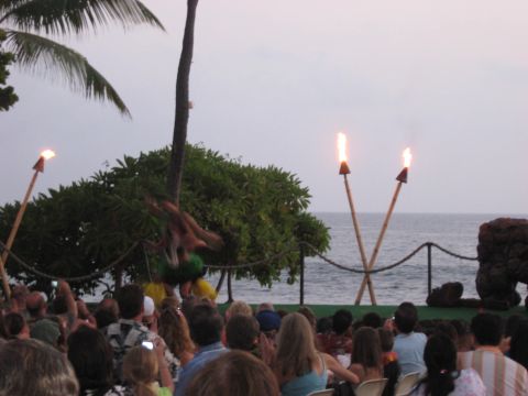 1991 Ford Bronco - A luau performance takes place outdoors by the ocean, with fire dancers and tiki torches illuminating the evening sky.