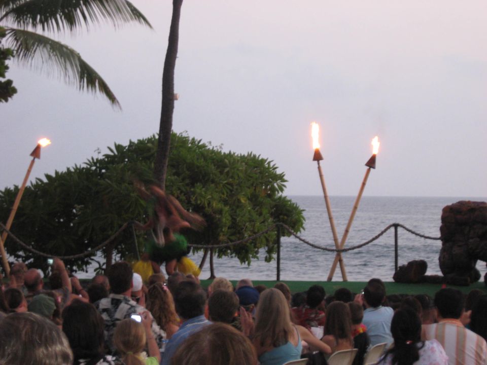 Outdoor luau performance with fire dancers and tiki torches by the ocean