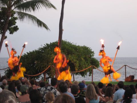 1991 Ford Bronco - A group of people in traditional attire perform a luau with fire torches on a stage near the ocean.