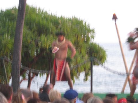 1991 Ford Bronco - A performer holds a seashell during a luau on a beach with the ocean in the background.