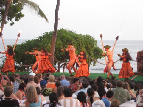 1991 Ford Bronco - A group performs a hula dance with torches on a stage overlooking the ocean, with an audience seated in the foreground.