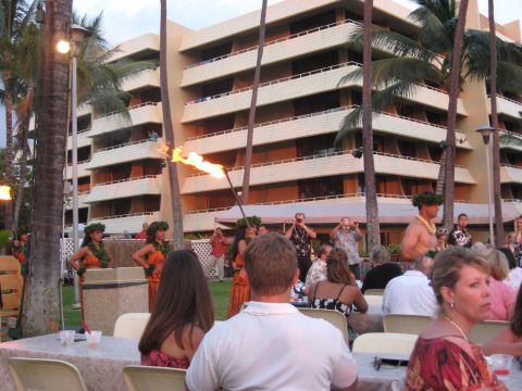1991 Ford Bronco - A fire dancer performs at a luau event with guests seated at tables and a hotel in the background.