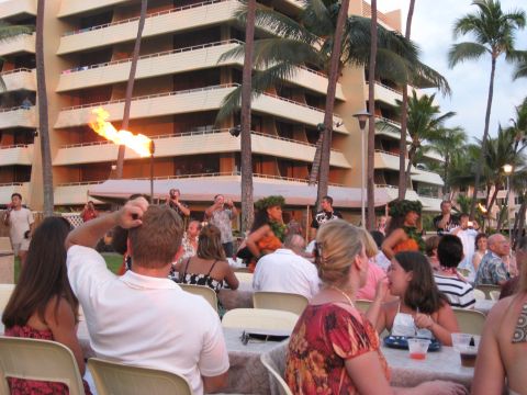 1991 Ford Bronco - An outdoor luau event with performers and spectators gathered in front of a hotel and palm trees.