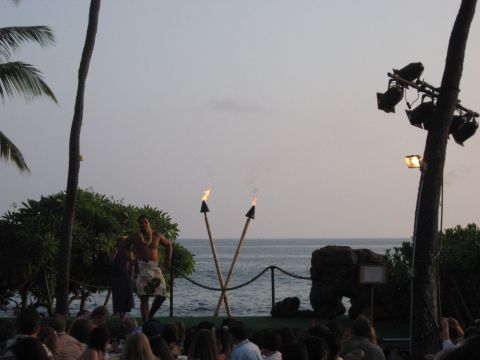 1991 Ford Bronco - A performer entertains an audience with fire torches during a luau event at dusk.