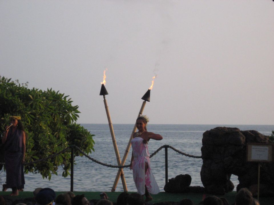 Hula dancers perform with flaming torches by the ocean