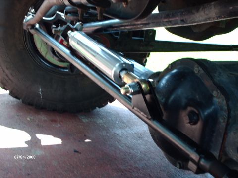 1982 Ford F-100 - This photo shows a steering assist cylinder, likely for off-road use, attached to the front axle and tie rod assembly.