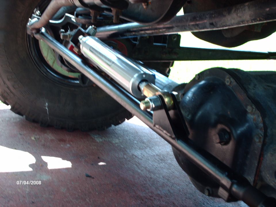 Chrome steering stabilizer mounted to tie rod and black solid front axle housing