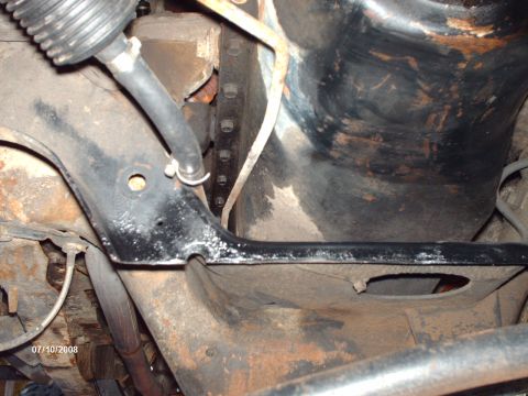 1982 Ford F-100 - Close-up of vehicle undercarriage components, including frame and hoses, with visible rust.