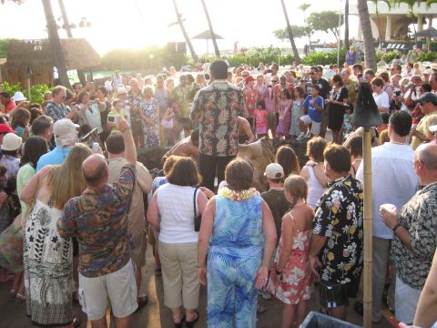 1991 Ford Bronco - An outdoor gathering of people, possibly a luau, with palm trees and resort buildings visible.