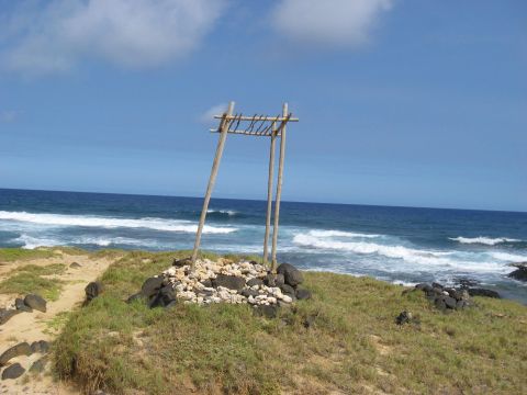 1991 Ford Bronco - Coastal landscape with a wooden frame structure and rocks on a grassy cliff by the sea.