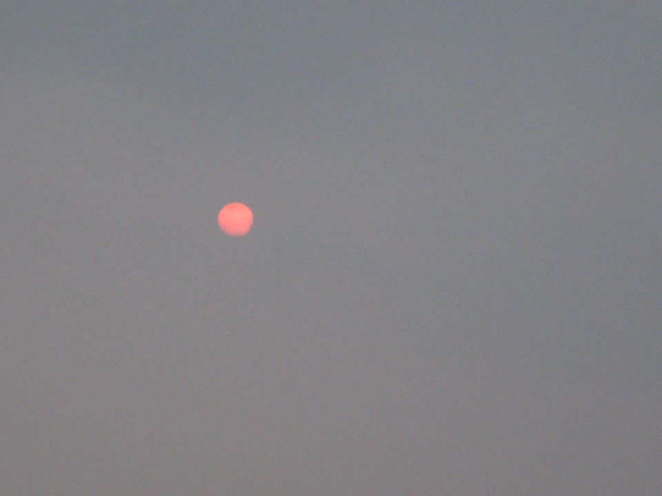 Red sun low in a hazy grey sky