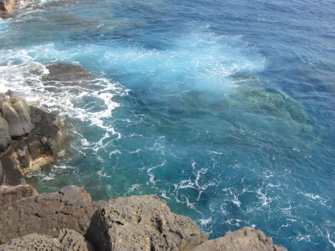 1991 Ford Bronco - Waves break on rocky shore, showing clear blue water and white foam.