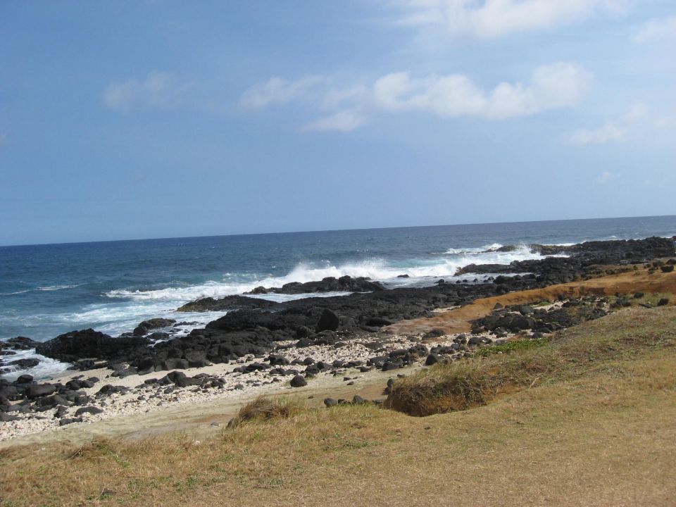Rocky coastline with waves crashing on shore under a blue sky