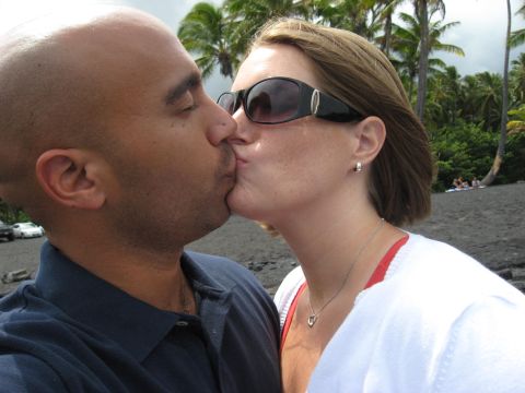 1991 Ford Bronco - A couple shares a kiss on a tropical beach with palm trees and a cloudy sky overhead.