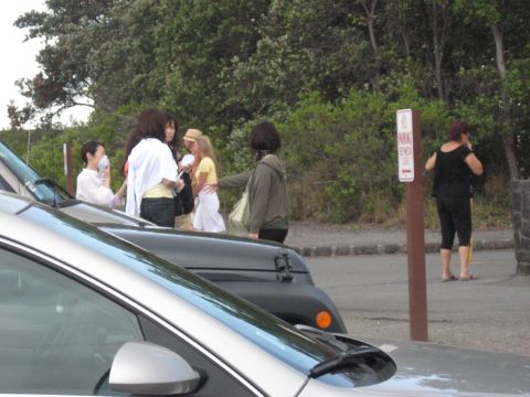1991 Ford Bronco - Several people are standing around parked vehicles, with a parking sign visible.