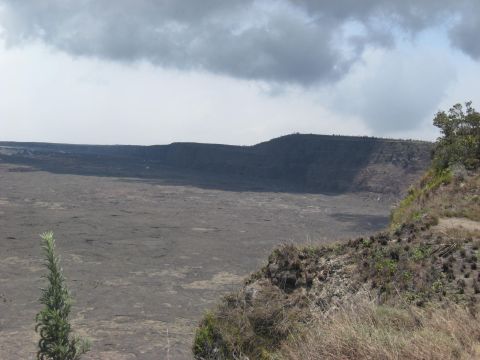 1991 Ford Bronco - A vast volcanic crater stretches out under a dramatic sky, with rocky terrain and sparse vegetation in the foreground.