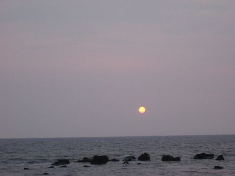 1991 Ford Bronco - The sun sets over the ocean, casting a soft glow on the water and rocks.