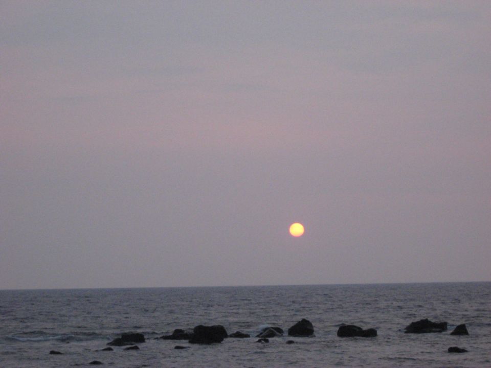 Sunset over the ocean with rocks.