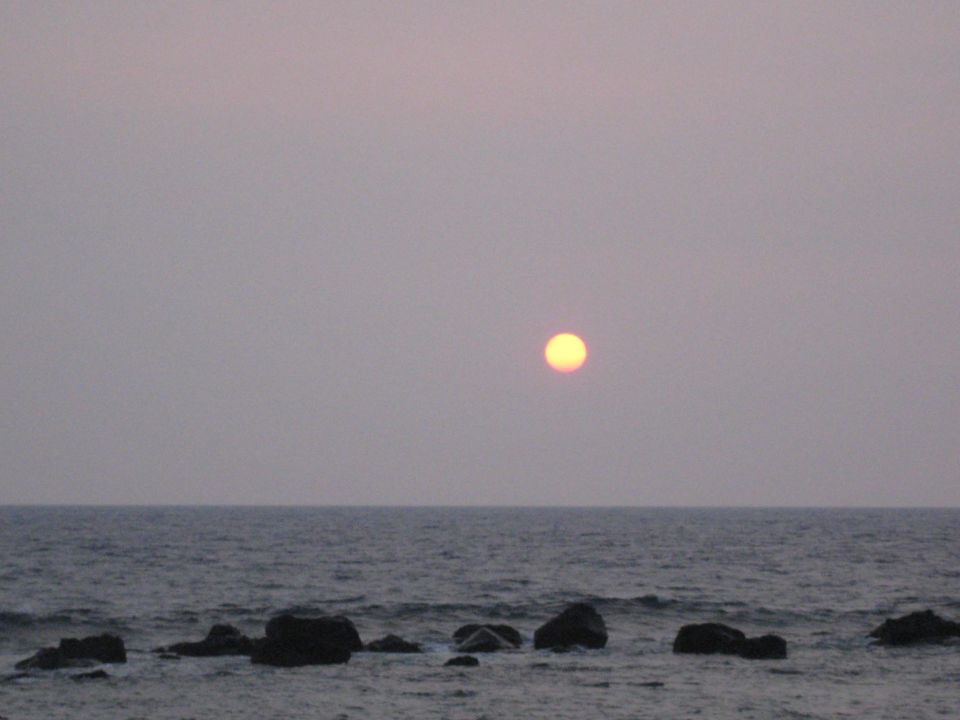Sunset over the ocean with rocks.