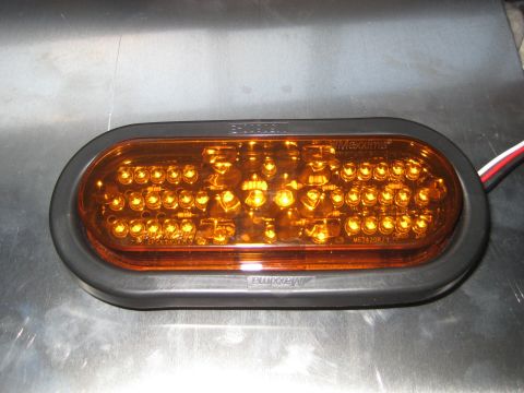1996 Ford Bronco - A close-up, eye-level view of an oval, amber LED trailer light with a black rubber gasket. The light is mounted on a metallic surface.