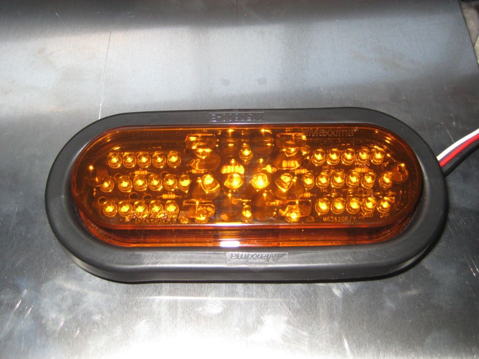 Oval amber LED trailer light with black gasket on metallic surface