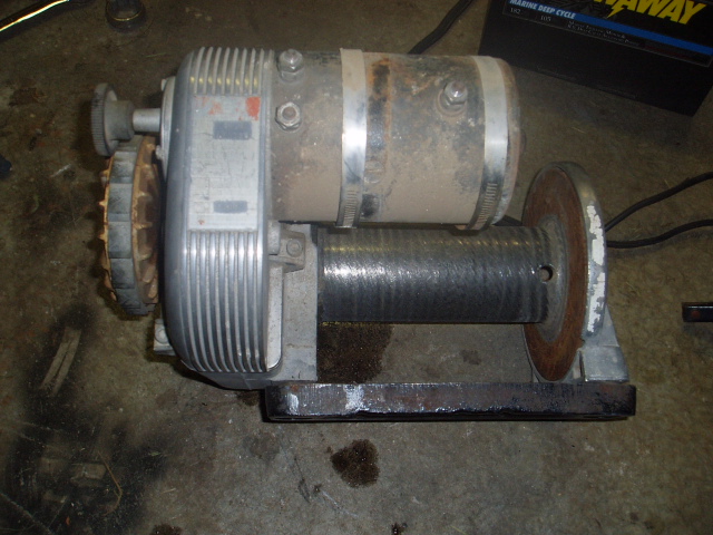 Dusty silver electric winch with metal drum on black base