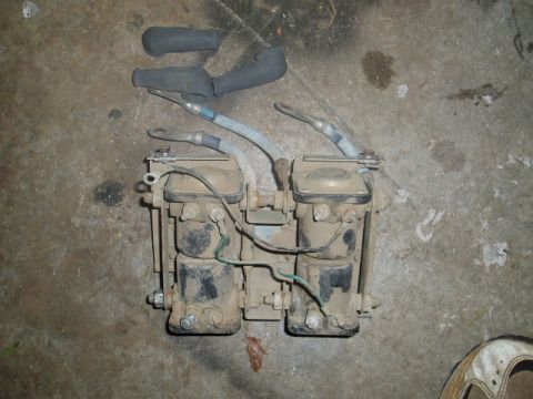 1980 Ford Bronco - A pair of ignition coils and spark plug wires are laid out on a concrete surface. The coils are dusty and appear to be from an older vehicl…