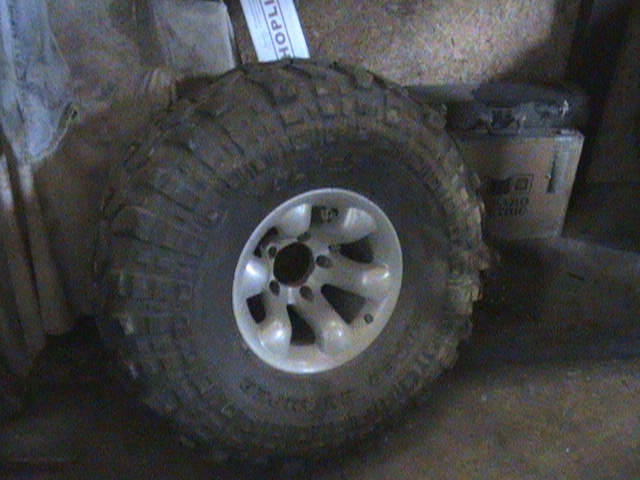 Mud-covered off-road tire and silver alloy wheel.