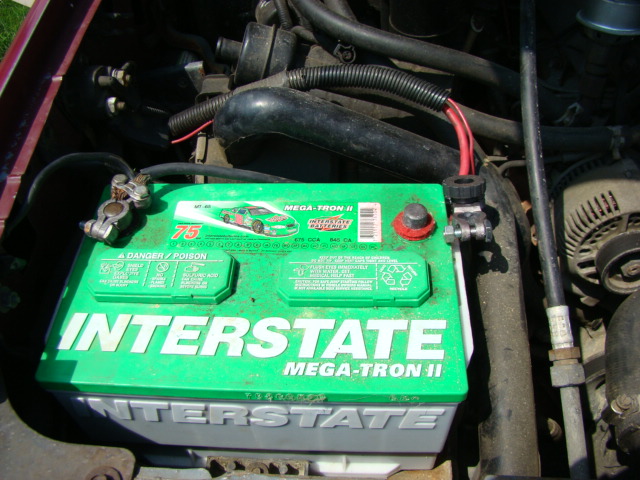 Green Interstate Mega-Tron II car battery with cables attached in a vehicle engine bay.