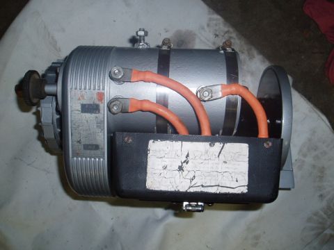1980 Ford Bronco - A silver electric motor or generator with orange cables connected to a black housing. The motor has ribbed fins on the casing and a label w…