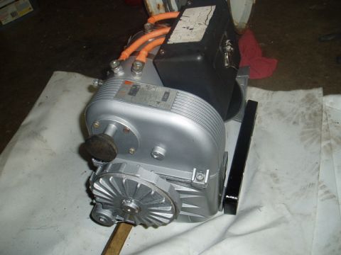 1980 Ford Bronco - A silver electric motor or gearbox assembly with orange cables is shown resting on a white cloth. A black housing is attached to the top of…