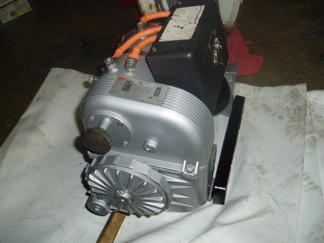 Silver electric motor assembly with orange cables and black housing.