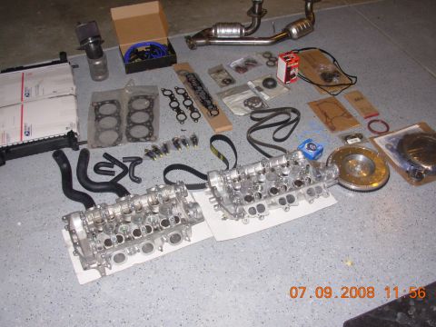 1988 Ford F-150 — Engine parts including cylinder heads, exhaust, radiator, and hoses on a gray floor.