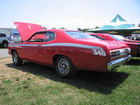 2001 Ford Crown Victoria - A red classic car with racing stripes and the number 340 is parked on grass next to another vehicle.