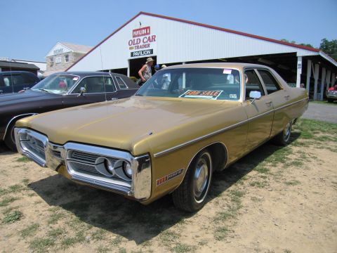 2001 Ford Crown Victoria - Gold sedan with a prominent grille and dual headlights, parked outdoors with a "FOR SALE" sign in the window.