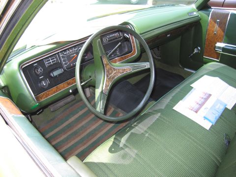 2001 Ford Crown Victoria - The interior of a vintage car features green upholstery, a wood-grain steering wheel, and striped floor mats.