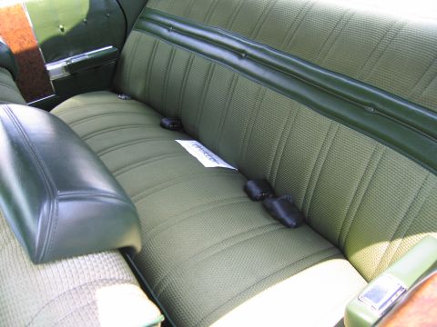 2001 Ford Crown Victoria - The interior of a car shows a green rear bench seat with black seatbelts and dark green vinyl accents.
