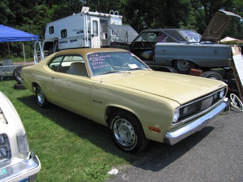 2001 Ford Crown Victoria - Photograph of a yellow Plymouth Duster at an outdoor swap meet, not a technical document.