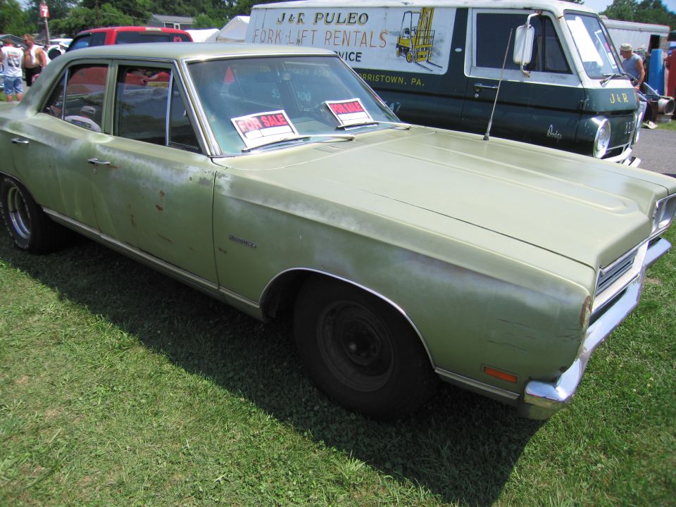 Faded green Plymouth sedan with for-sale signs in windows