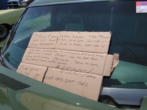 2001 Ford Crown Victoria - A sign with handwritten text is affixed to the windshield of a vehicle.