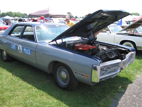 2001 Ford Crown Victoria - A vintage state police car is displayed with its hood open, revealing the engine compartment.