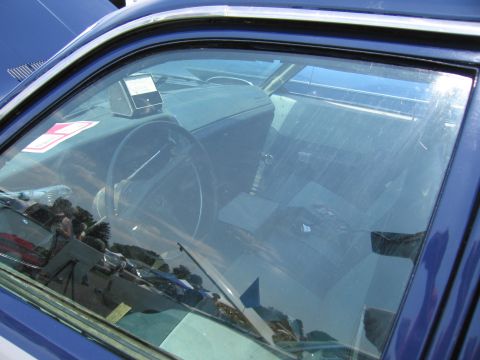 2001 Ford Crown Victoria - Interior of a blue vehicle, showing the dashboard, steering wheel, and seats through the window.