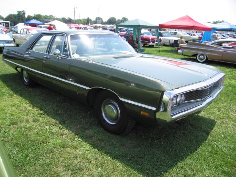 2001 Ford Crown Victoria - A vintage green sedan is displayed on a grassy field under tents at a car show.