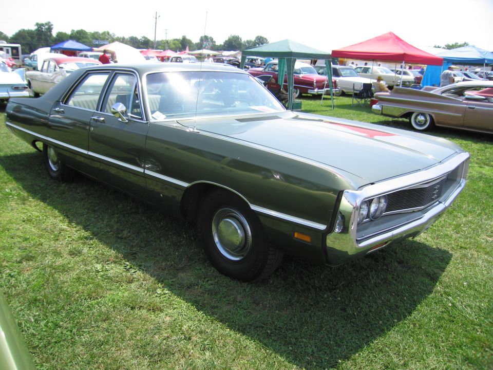 Green sedan with chrome grille and trim, parked on grass at an outdoor event