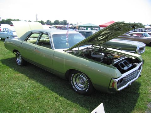 2001 Ford Crown Victoria - A green sedan from the 1970s is displayed with its hood open at an outdoor event.
